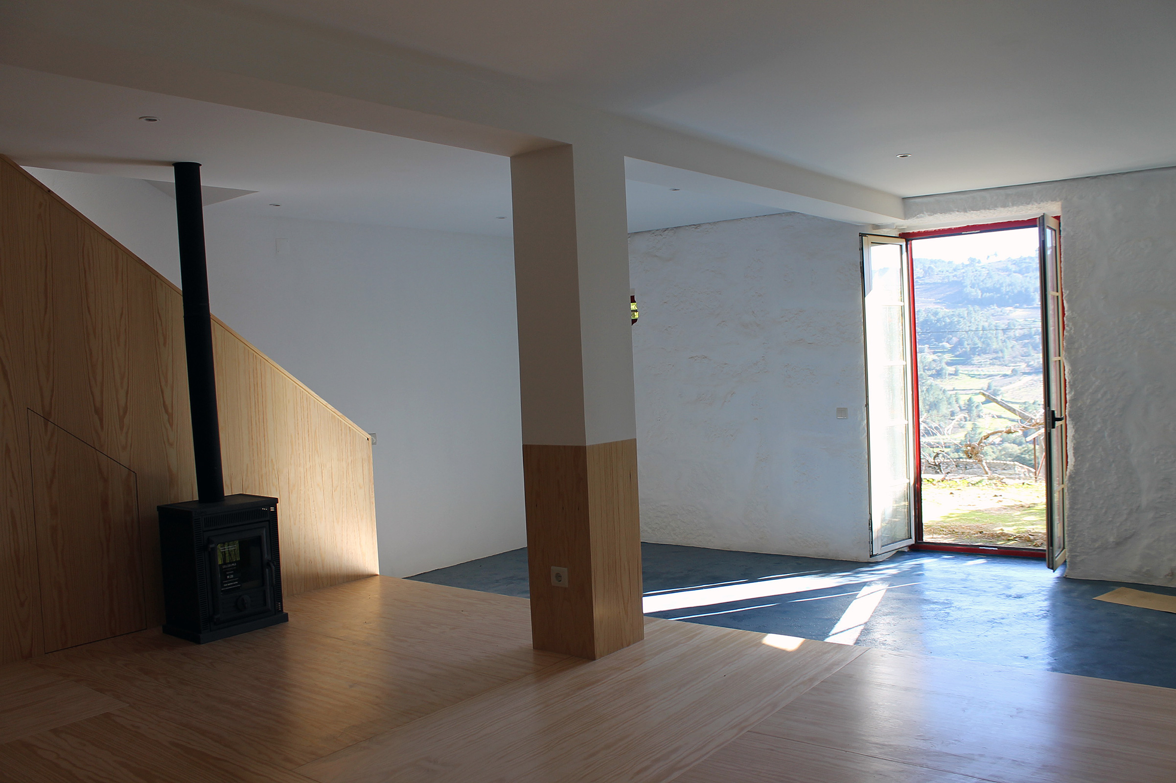 Nova sala de estar em madeira, cimento alisado e pedra à vista pintada para maior luminosidade